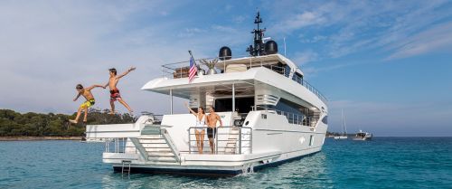 Deux garçons sautant de la plateforme de bain d'un bateau pendant des vacances en famille sur un yacht de location