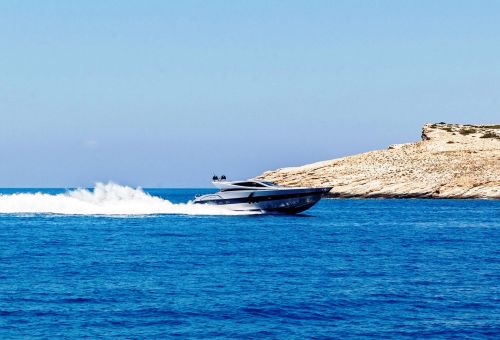 Un yacht à moteur sportif naviguant le long de la côte de Santorin