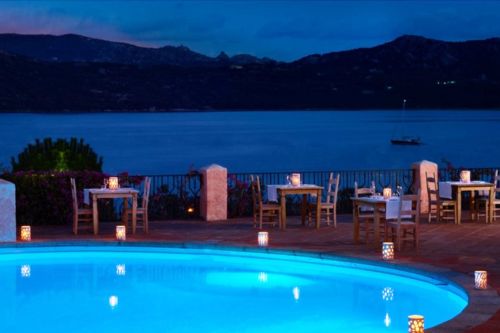 La piscine du restaurant Mira Luna avec vue sur la baie de Cannigione et quelques tables dressées pour le dîner