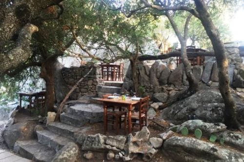 Des tables dressées dans un jardin rocailleux au restaurant traditionnel Pedristellas à Porto Rotondo