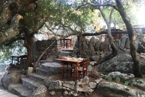 Des tables dresses dans un jardin rocailleux au restaurant traditionnel Pedristellas  Porto Rotondo