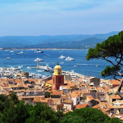 Le village de Saint-Tropez avec son beau clocher et des yachts de location  l'ancre dans la baie