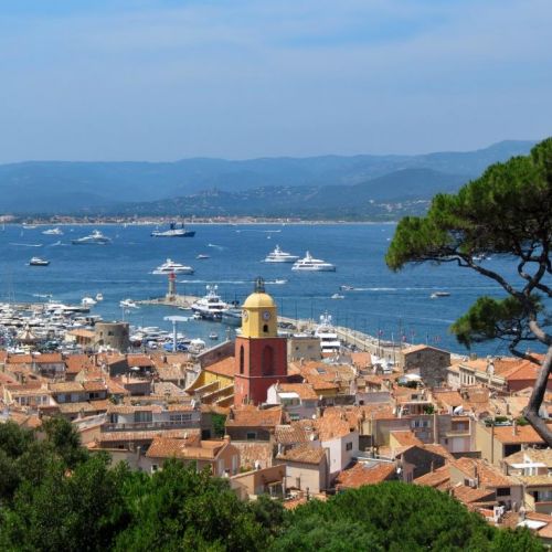 Le village de Saint-Tropez et son clocher avec des yachts  l'ancre dans la baie