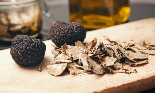 Deux truffes blanches et des copeaux sur une planche en bois d'olivier