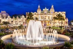 Le casino de Monaco vu de nuit avec ses éclairages et une fontaine sur la place