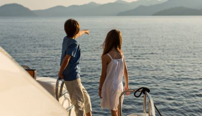 Des enfants regardant la mer depuis un yacht de location avec leurs parents sur le pont arrire