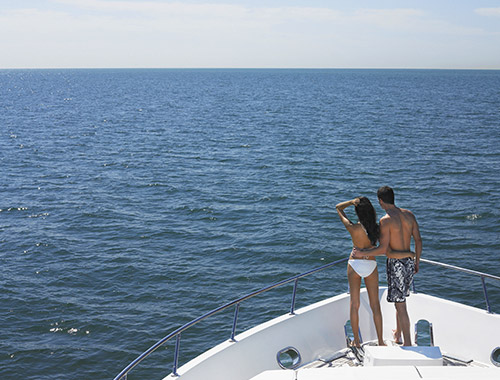 Un couple en maillot de bain se tenant  la proue d'un yacht de location lors de leur croisire d't en Mditerrane